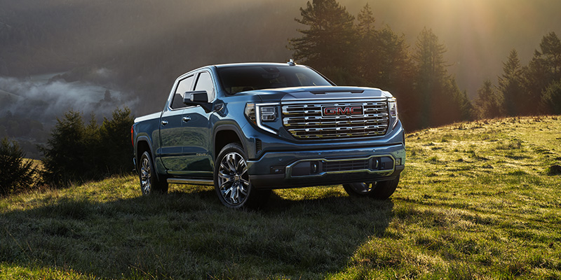 A 2026 GMC Sierra 1500 parked in a green meadow in the mountains