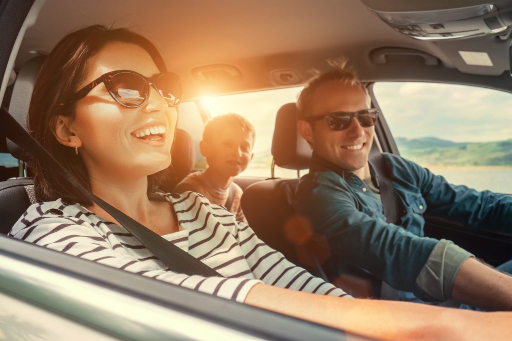 A Laughing Family in a GMC SUV On A Summer Road Trip with the sun shining in through the window.